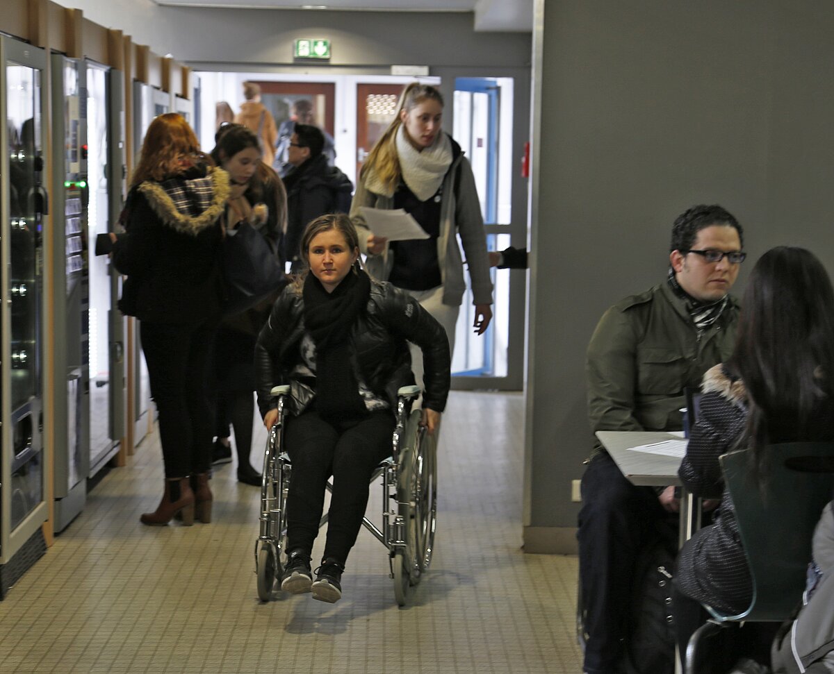 Etudiante en fauteuil roulant à la céfétaria du bâtiment du Patio